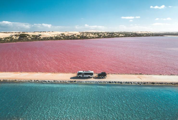 Transporter mit einem kleineren Auto im Schlepptau auf einer unbefestigten Straße zwischen dem rosafarbenen Lake MacDonnell und dem Green Lake auf der Eyre Peninsula, Südaustralien © Jaxon Foale