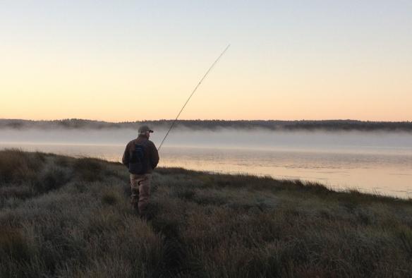 Ein Mann beim Angeln am Ufer eines von Nebelschwaden bedeckten Sees bei Sonnenuntergang, Central Highlands, Tasmanien © Driftwater