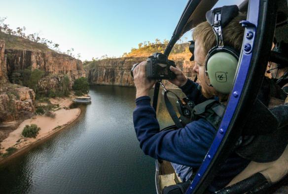 Eine Person macht ein Foto aus einem Hubschrauberfenster über einer malerischen Outback-Schlucht, Nitmiluk Tours, Nitmiluk National Park, Northern Territory © Tourism Australia