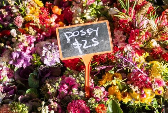 A close up photo shows vibrant pink, purple, orange and yellow posies bunched together in a market stall at the Capital Region Farmers Market, Canberra, Australian Capital Territory © Tourism Australia