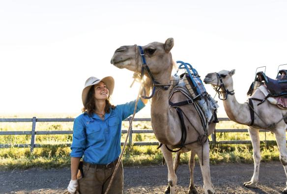Tour guide petting a camel, Summer Land Camels, Harrisville, Queensland © Tourism Australia