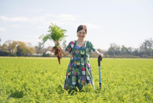 A woman stands in a field holding carrots, Scenic Rim Farm Shop and Cafe, Kalbar, Queensland © Tourism Australia