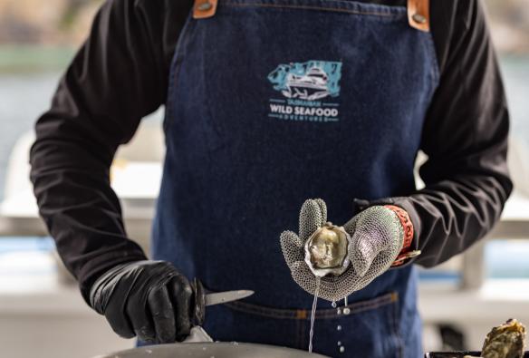 A man holding a shucked oyster, Tasmanian Wild Seafood Adventures, Hobart, Tasmania © Dearna Bond