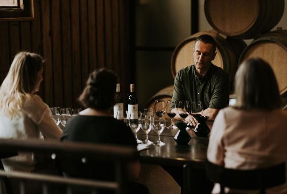 In a moody barrel room, a wine specialist walks guests through a tasting flight of wines at Vasse Felix, Australia’s South West, Western Australia © Tourism Australia