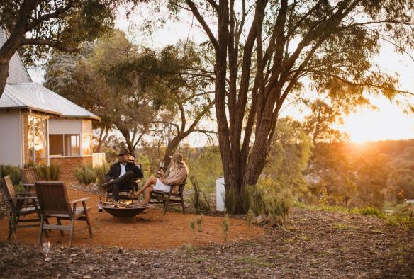 Two people sit by an outdoor fireplace enjoying glasses of wine at Ampersand Estates Winery, Australia’s South West, Western Australia © Tourism Australia