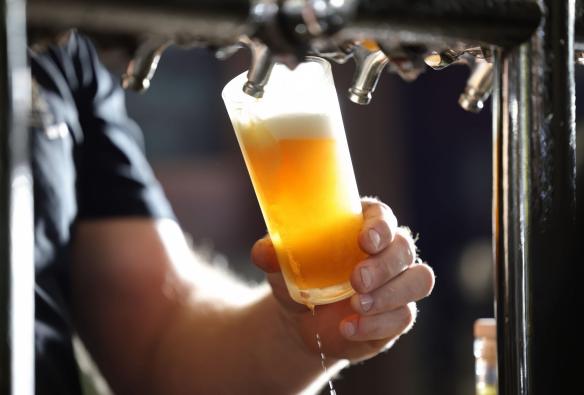 A close up shows a bar tender pulling a small glass of beer from the beer taps at Black Duck Brewery, Barrington Coast, New South Wales © Tourism Australia