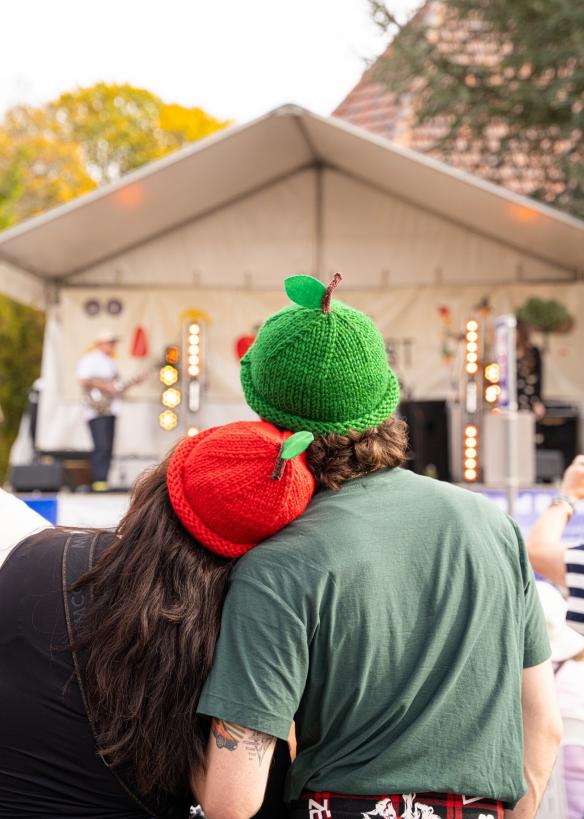 Two people wearing knitted hats in the shape of apples at Batlow Cider Fest, Riverina, New South Wales © Batlow Cider Fest