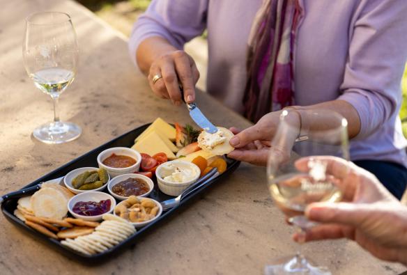 Two friends enjoy glasses of white wine and a platter of cheese at Tintilla Estate in Pokolbin, New South Wales © Destination NSW