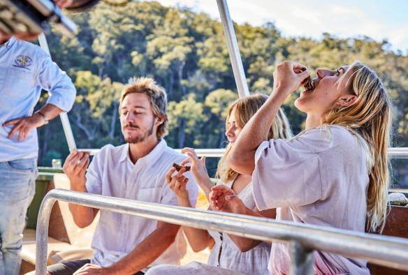 People eating fresh oysters on a boat during a tour with Captain Sponge's Magical Oyster Tours, South Coast, New South Wales © Tourism Australia