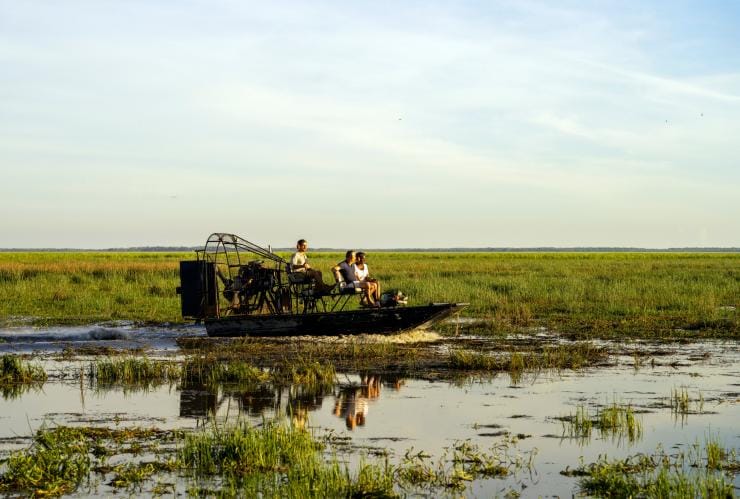 Three people on an air boat driving through wetlands, Bamurru Plains, Kakadu, Northern Territory © Tourism NT/KWP!/Shaana McNaught
