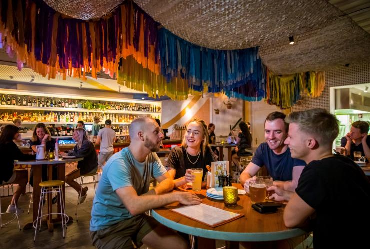 A group of four friends chatting at a table in a colourful hotel, The Imperial Hotel, Sydney, New South Wales © Destination NSW