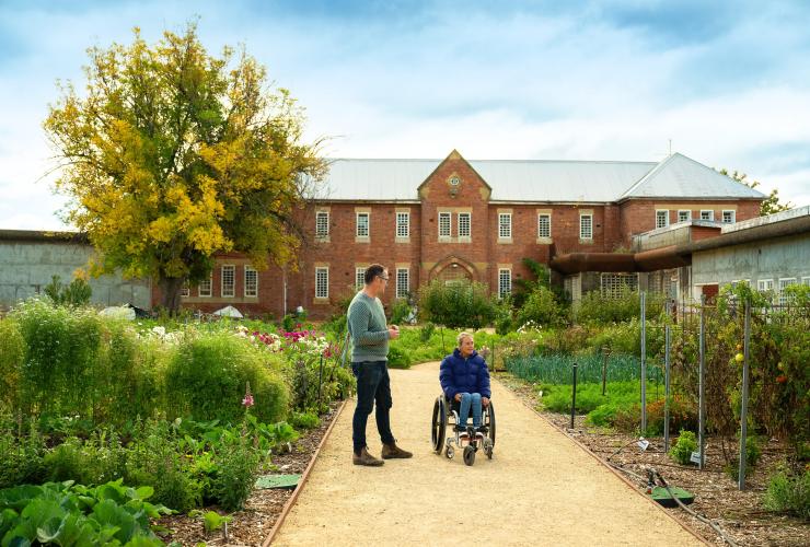 A person in a wheelchair with a guide exploring a kitchen garden, The Agrarian Kitchen, Southern Tasmania, Tasmania © Tourism Australia