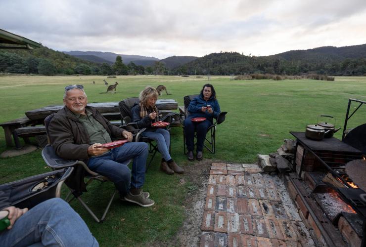 A group of people dining in camp chairs with kangaroos in the background, Pepper Bush Adventures, Scottsdale, Tasmania © Tourism Australia