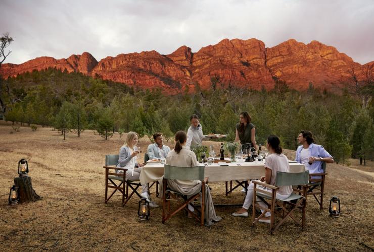 Group dining outdoors beside a rugged mountain range, Arkaba, Flinders Ranges, South Australia © Wild Bush Luxury