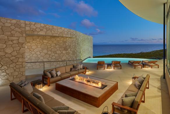 A balcony with lounges surrounding a fire pit, deck chairs lining a small pool and sweeping views of the ocean beyond during dusk at Southern Ocean Lodge, Kangaroo Island, South Australia © George Apostolidis Photography