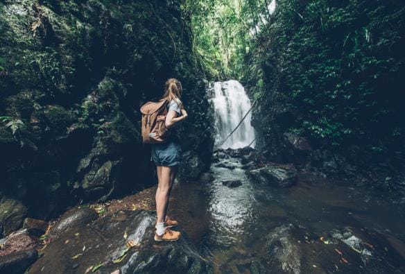 A girl standing with a backpack at the edge of Box Log Falls in Lamington National Park, Queensland © Tourism and Events Queensland