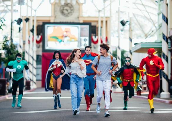 A couple runs along with hero mascots at Warner Brothers Movie World, Gold Coast, Queensland © Tourism Australia