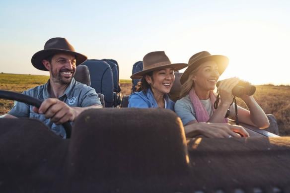Two women look through binoculars while riding in a jeep with a guide from Point Stuart Wilderness Lodge, Kakadu National Park, Northern Territory © Tourism & Events NT/Safari Global