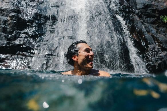 Man smiles under the mist of a waterfall in Kakadu National Park, Northern Territory © Tourism & Events NT/@Ben.Savage