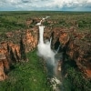 Aerial view over a large waterfall cascading off a cliff amid lush green bushland. Jim Jim Falls, Kakadu National Park, NT © Jarrad Seng, all rights reserved