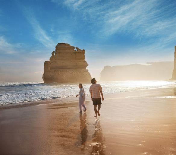Couple walking along the beach with the 12 Apostles in the background © Tourism Australia