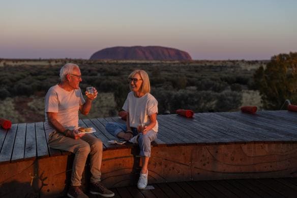 Couple enjoys drinks with Uluru in the background at  Wintjiri Wiru, Uluru-Kata Tjuta National Park, Northern Territory © Tourism Australia