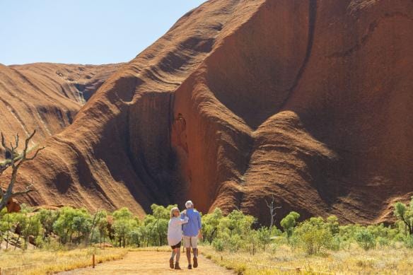 A couple walks down a sandy path toward Uluru, Uluru-Kata Tjuta National Park, Northern Territory © Tourism Australia