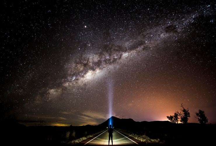 A person stargazing in the outback with a head torch pointed up toward a bright constellation, Warrego Way, Queensland © Tourism and Events Queensland
