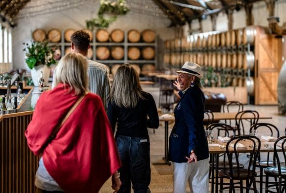 A friendly, smiling tour guide shows a group of people through a winery barrel room, Epic Taste Experiences, Geelong and the Bellarine, Victoria © Epic Taste Experiences
