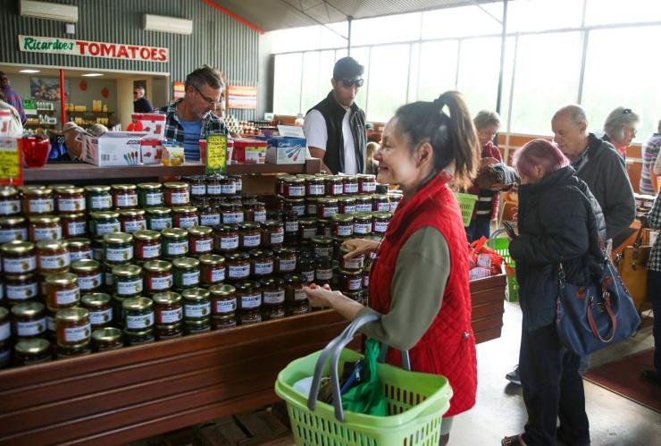 The busy farm shop at Ricardoes Tomatoes & Strawberries has many customers walking through looking at the homemade rows of jams, preserves and fresh produce, Barrington Coast, New South Wales © Tourism Australia