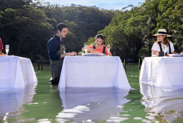 Couple at a table in the water tasting oysters at Sydney Oyster Farm Tours, Mooney Mooney, New South Wales © Tourism Australia