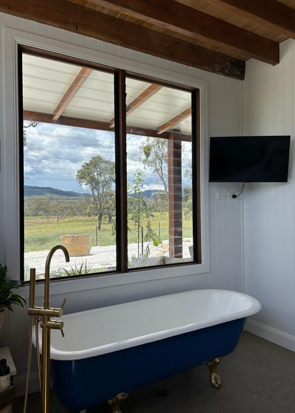 Bathtub with a view of bushland out the window at The Barn, Tenterfield Tiny Farm, Tenderfield, New South Wales © The Barn