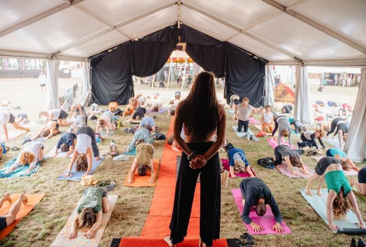 A group of people doing a yoga class under a tent at a festival, Party in the Paddock, Carrick, Tasmania © Cameron Jones