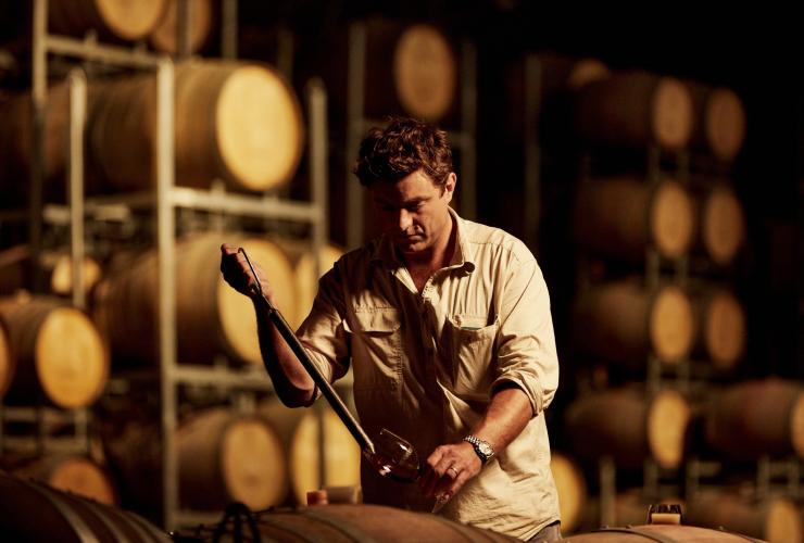 A winemaker working in a cellar filled with barrels, Brokenwood Wines, Hunter Valley, New South Wales © Destination NSW