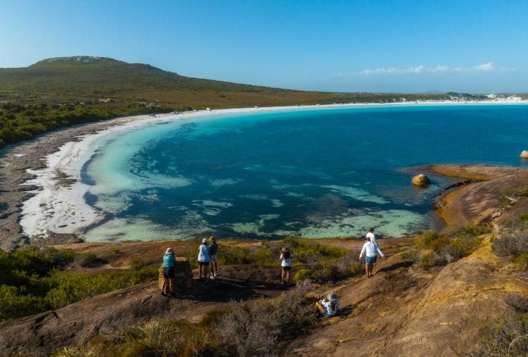 A group of people standing on a headland overlooking a white sand beach fringed by thick bushland and clear blue water with Untamed Escapes, Esperance, Western Australia © Tourism Australia