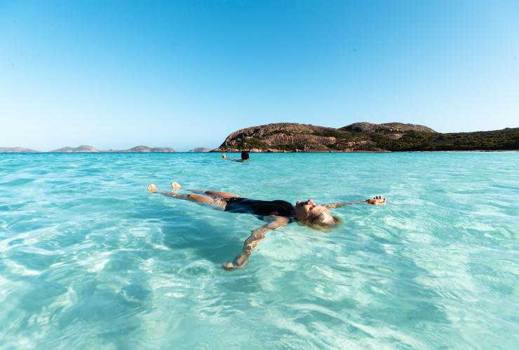 A person floating in the clear, bright blue ocean on a sunny day with Untamed Escapes, Esperance, Western Australia © Tourism Australia