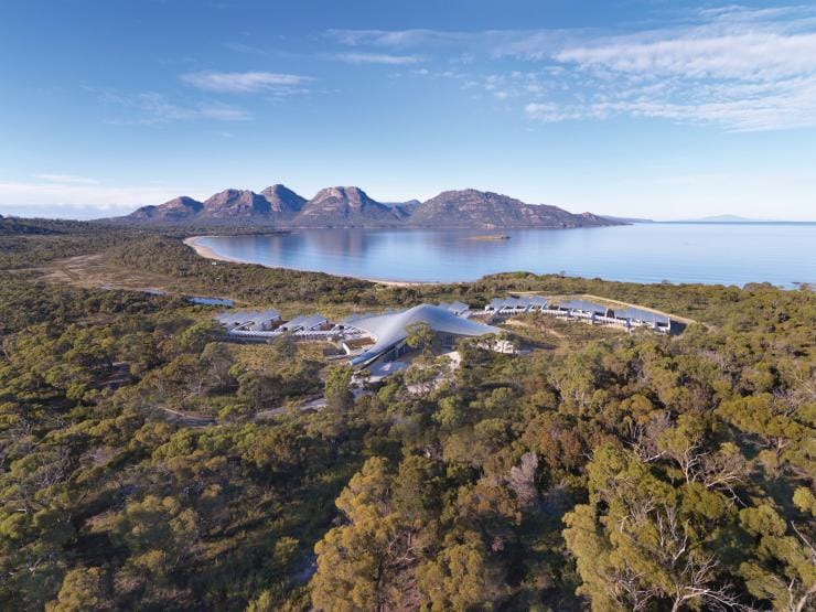 Aerial view over a luxurious lodge surrounded by bushland with a calm bay and mountains in the distance, Saffire Freycinet, Freycinet, Tasmania © Saffire Freycinet