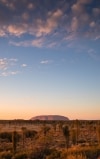 A large red rock monolith rising from the flat outback landscape at Uluru, Uluru-Kata Tjuta National Park, Northern Territory © Tourism Australia