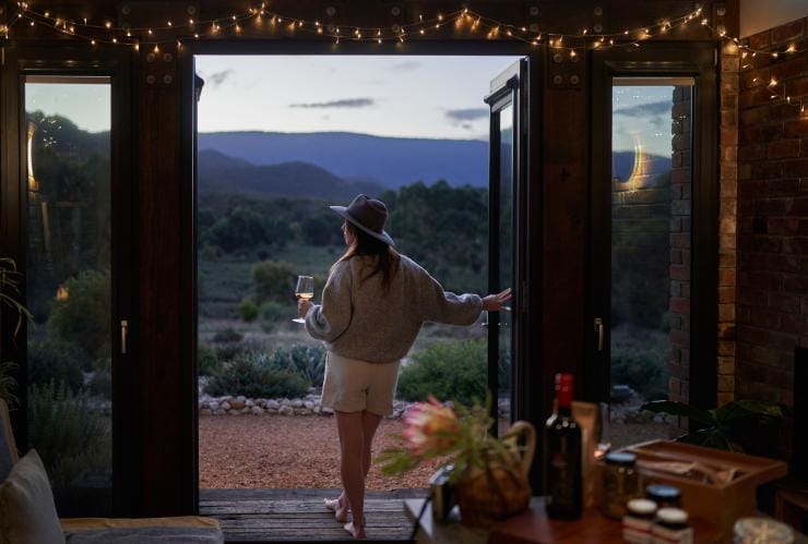 A person sipping a glass of wine while watching bushland scenery during dusk, Nook on the Hill, Grampians, Victoria © Visit Victoria