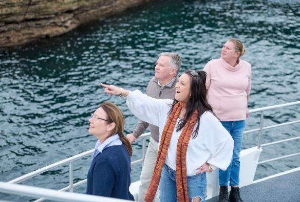 A woman points out to the ocean from a boat tour with Jervis Bay Wild, Jervis Bay, New South Wales © Tourism Australia
