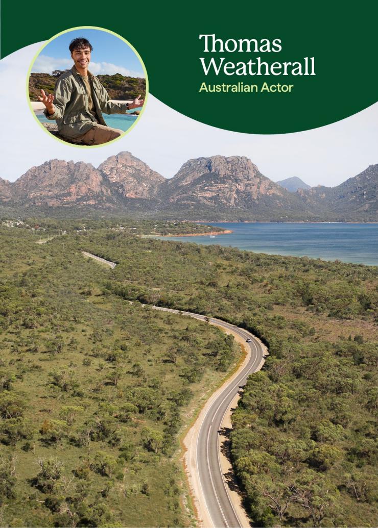 Aerial view over a road winding through bushland with mountains and a large body of water in the distance, an overlaid image shows a man smiling with the caption "Thomas Weatherall, Australian Actor"