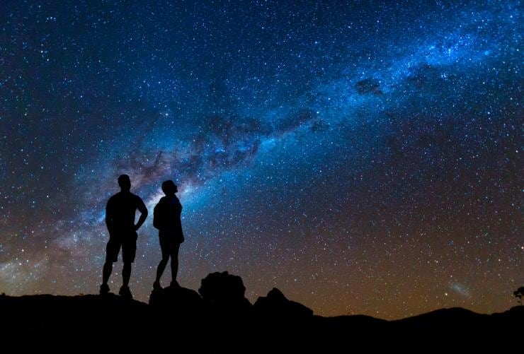 Two people standing on a ledge at night looking up at a sky full of stars, Arkaroola Wilderness Sanctuary, Flinders Ranges & Outback, South Australia © South Australian Tourism Commission