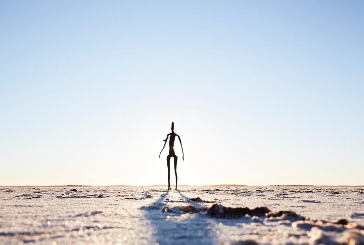 A dry salt lake with a sculpture of a person, Antony Gormley Sculptures at Lake Ballard, Golden Outback, Western Australia © Robert Gray Photography