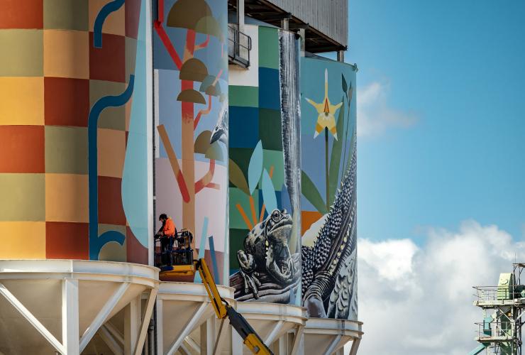 A person on a forklift painting a series of colourful murals on silos along the PUBLIC Silo Trail, Newdegate, Western Australia © Bewley Shaylor
