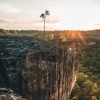 An Aboriginal tour guide and two guests standing on a rocky outcrop overlooking green bushland during a tour with Jarramali Rock Art Tours, Tropical North Queensland, Queensland © Tourism Tropical North Queensland 