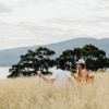A couple picnicking on a grassy hill overlooking the ocean on Satellite Island, Tasmania © Adam Gibson