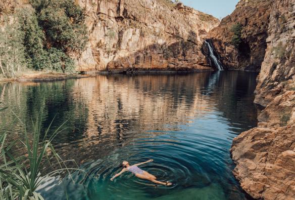 A person floating on their back in the clear, blue-green waters of Barramundi Gorge (Maguk), Kakadu National Park, NT © Tourism Northern Territory/Adriana Alvarado