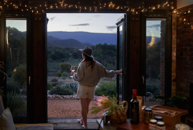 A person sipping a glass of wine while watching bushland scenery during dusk, Nook on the Hill, Grampians, Victoria © Visit Victoria