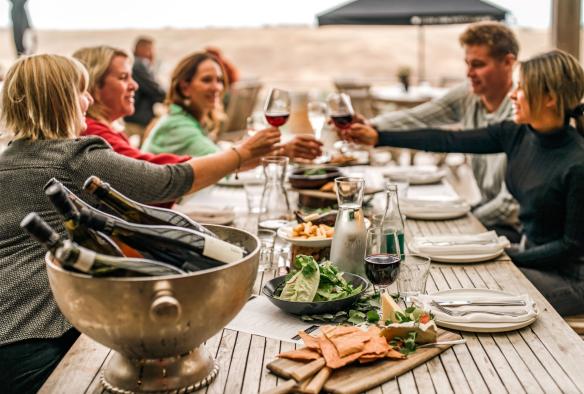 A group of diners sit on the deck of a winery, overlooking the rolling country landscape. They are all charging their glasses, toasting one another, with wine from the winery, Epic Taste Experiences, Geelong and the Bellarine, Victoria © Epic Taste Experiences