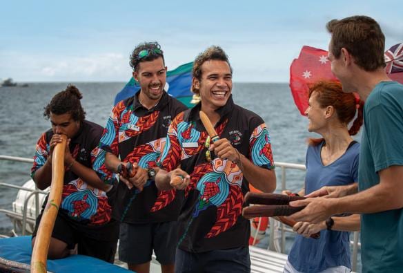 Aboriginal tour guides performing using clapping sticks and didgeridoos on a boat during a tour with Dreamtime Drive and Snorkel, Great Barrier Reef. Cairns, Queensland © Archie Sartracom